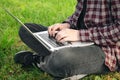 Man in the park sitting on the grass with a laptop, close-up hands and laptop. Royalty Free Stock Photo