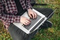 Man in the park sitting on the grass with a laptop, close-up hands and laptop. Royalty Free Stock Photo