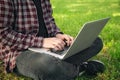 Man in the park sitting on the grass with a laptop, close-up hands and laptop. Royalty Free Stock Photo
