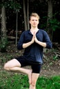 Man in Park stands in Yoga Tree Pose