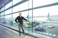 Man, a passenger, waiting for his flight, stands at the window and looks at the airport runway, a travel concert Royalty Free Stock Photo