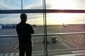 Man, a passenger, waiting for his flight, stands at the window and looks at the airport runway, a travel concert Royalty Free Stock Photo