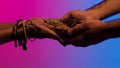 Man passes a plate of spices to indian woman with many bracelets and mehendi on her hands, isolated on bright background Royalty Free Stock Photo