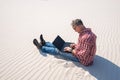 Man is passionate about work, with a laptop sits in desert Royalty Free Stock Photo