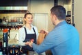 Man paying takeaway order by credit card on reader holded by smiling waitress working at shop counter restaurant. Royalty Free Stock Photo