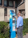 Man pays parking machine by coin. Sunny day Sentendre Hungary.