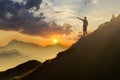 Man on peak of mountain. Emotional scene. Young man with backpack standing with raised hands on top of a mountain and enjoying mo