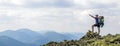 Man on peak of mountain. Emotional scene. Young man with backpack standing with raised hands on top of a mountain and enjoying mo Royalty Free Stock Photo