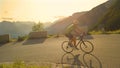 Man pedalling his road bicycle up a steep asphalt road in Slovenian mountains.