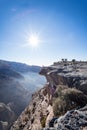 Man peeking over the cliff with the sun in the background at the Grand Canyon of Jebel Shams, Oman Royalty Free Stock Photo