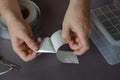 A man is peeling aluminum tape off the paper backing. The proces