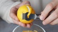 Man peeling fresh lemon with zester, closeup view