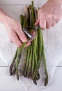 Man peeling green asparagus. White wooden background. Men`s hands and organic fresh asparagus Royalty Free Stock Photo