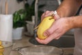 A man peels potatoes with a vegetable peeler in a bright kitchen. Preparation of potatoes for cooking. Cleaning peel