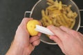 A man peels potatoes with a vegetable peeler, cuts out the lateral bud, the eye. Preparation of potatoes for cooking