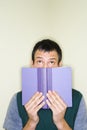 Man peering over top of book