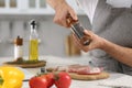 Man peppering steak at table in kitchen, closeup. Online cooking course Royalty Free Stock Photo