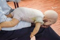 Man performing CPR on baby training doll dummy with one hand compression. First Aid Training - Cardiopulmonary resuscitation.