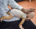 Man performing CPR on baby training doll dummy with one hand compression. First Aid Training - Cardiopulmonary resuscitation.