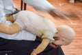 Man performing CPR on baby training doll dummy with one hand compression. First Aid Training - Cardiopulmonary resuscitation.