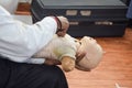 Man performing CPR on baby training doll dummy with one hand compression. First Aid Training - Cardiopulmonary resuscitation.