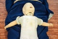 Man performing CPR on baby training doll dummy with one hand compression. First Aid Training - Cardiopulmonary resuscitation.