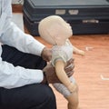 Man performing CPR on baby training doll dummy with one hand compression. First Aid Training - Cardiopulmonary resuscitation.