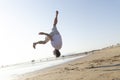 Man performing a dynamic backflip on a sandy beach Royalty Free Stock Photo