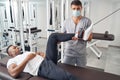 Man performing leg exercise assisted by certified physiatrist