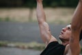 Man performing pull ups outdoors, focused on training and strength, with cross tattoo on forearm Royalty Free Stock Photo