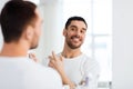 Man with perfume looking to mirror at bathroom