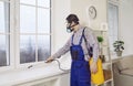 Man from Pest Control Service spraying insecticide over window frame inside the house Royalty Free Stock Photo
