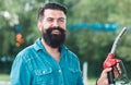 Man on petrol pump filling nozzles. Gas station. Portrait of bearded man hold fueling nozzle gasoline, fuel pump. Royalty Free Stock Photo