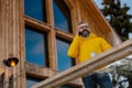 Man phone calling from patio, drinking hot tea, coffee and enjoying beautiful winter day. Handsome man spending relaxing Royalty Free Stock Photo