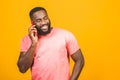 Man on the phone. Cheerful black man talking on the mobile phone and smiling while standing isolated on yellow background Royalty Free Stock Photo