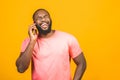 Man on the phone. Cheerful black man talking on the mobile phone and smiling while standing isolated on yellow background Royalty Free Stock Photo