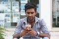 Man phone. Closeup portrait angry indian male holding texting looking at cellphone isolated outdoors background