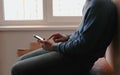 Man with phone. Unrecognizable young man chatting in mobile phone sitting on balcony near the window