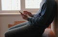 Man with phone. Unrecognizable young man chatting in mobile phone sitting on balcony near the window