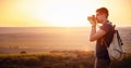 Man photographer with backpack and camera taking photo of sunset mountains Royalty Free Stock Photo