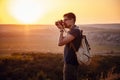 Man photographer with backpack and camera taking photo of sunset mountains Royalty Free Stock Photo