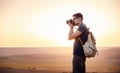 Man photographer with backpack and camera taking photo of sunset mountains Royalty Free Stock Photo