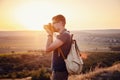 Man photographer with backpack and camera taking photo of sunset mountains Royalty Free Stock Photo