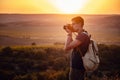 Man photographer with backpack and camera taking photo of sunset mountains Royalty Free Stock Photo