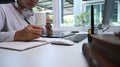 A man photographer drinking coffee and writing some notes in notebook while sitting at his office desk. Royalty Free Stock Photo