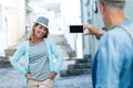 Man photographing smiling woman in city