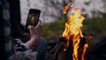 A man photographs a bonfire on a smartphone. Camping. Hiking in the mountains. Tourism. Travel