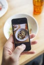 A man photographs a delicious salad on his phone in a restaurant Royalty Free Stock Photo