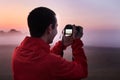 A man photographs a dense fog on an early morning at dawn