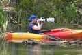 Man photographs while in kayak.